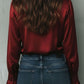 Uma elegante blusa de cetim cor de vinho com mangas largas e detalhes em renda 2025